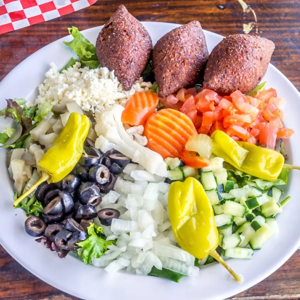 Gyro Guys' kibbeh platter with three kibbeh, feta, olives, tomatoes, cucumbers, and pickled vegetables.