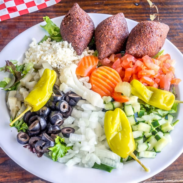 Gyro Guys' kibbeh platter with three kibbeh, feta, tomatoes, olives, peppers, and mixed greens.