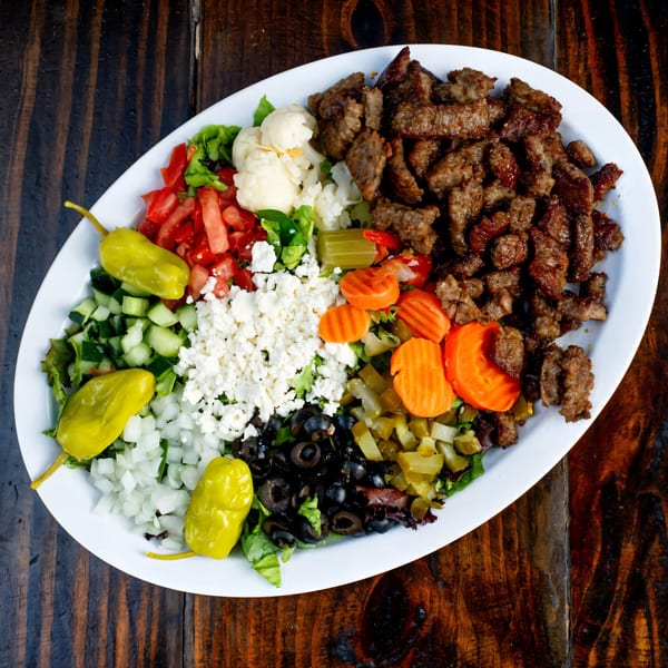 Gyro Guys' large platter with gyro meat, lettuce, tomatoes, cucumbers, feta, olives, and pickled vegetables.